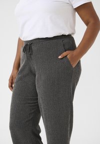 Gray elastic waist pants with textured fabric, featuring a drawstring closure and side pockets. The design has subtle vertical lines.
