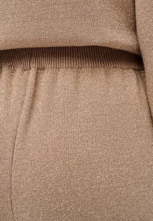 Gestrickter Pullover in Beige mit dezentem goldenem Faden, ausgestattet mit einem gerippten Bund und einer weichen Textur. Nahaufnahme mit Fokus auf die Stoffdetails.