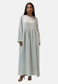 Robe longue en satin argenté avec manches longues, encolure ronde et taille froncée. Texture transparente et silhouette fluide.