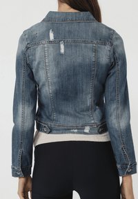 Chaqueta de mezclilla en azul desgastado con detalles de desgaste, corte entallado, cuello clásico y botones en la cintura y los puños.