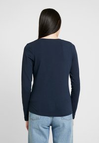 Marinblå långärmad t-shirt i bomull med rundad hals och figurnära design, med minimala sömmar och en slät yta. Avslappnad stil, vy bakifrån.