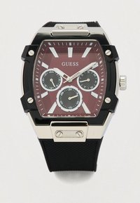 Czarny zegarek z żywicy z prostokątną, czerwono teksturowaną tarczą, srebrnymi akcentami, trzema podtarczami oraz czarnym gumowym paskiem. Zegarek posiada wyraźne oznaczenia godzin.