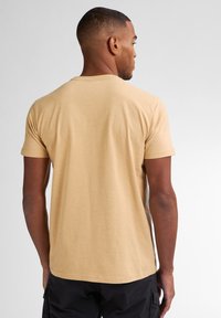 Tan kortarmige t-shirt van lichtgewicht stof, met een ronde hals en een lichte gemêleerde textuur. Geen zichtbare logo's of patronen.