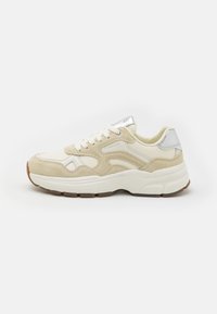Basket en suède et cuir beige avec une finition texturée, semelle en caoutchouc blanc et accents argentés. Comprend une languette rembourrée et un système de laçage.