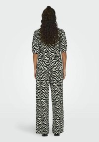 Černo-bílé zebra vzorované oblečení obsahující krátký rukáv s nabíranými rukávy a široké kalhoty vyrobené z lehké tkaniny.