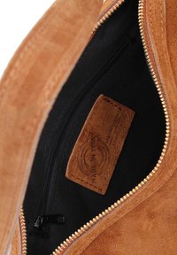 Bruine suède tas met een open gouden rits die de zwarte binnenvoering toont en een "Made in Italy" leren label aan de binnenkant.