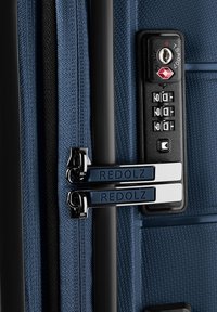 Gros plan d'une valise rigide bleue avec double tirette de fermeture éclair et un cadenas à combinaison TSA réglé sur 0-0-0.
