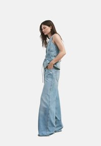 Conjunto de denim azul claro que presenta una blusa sin mangas con cintura ajustable y pantalones de pierna amplia. La tela tiene un acabado suave y Texturizado.
