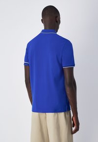 Royalblaue Polohemd mit klassischem Design. Verfügt über kurze Ärmel, einen Kragen, weiße Akzente an den Ärmeln und einen geraden Schnitt am Saum.