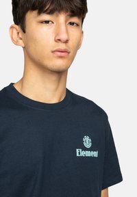 Navy Baumwoll-T-Shirt mit einem hellblauen "Element"-Logo auf der Brust, Rundhalsausschnitt und kurzen Ärmeln, glatte Textur.