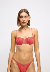 Κόκκινο δαντελένιο σουτιέν με μπανέλα, με λουλουδάτα σχέδια και ρυθμιζόμενες τιράντες. Συνδυάζεται με αντίστοιχο κόκκινο δαντελένιο στρινγκ. Λείο υφ surface.
