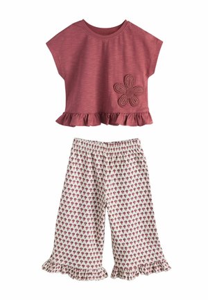 Mädchen-Zweiteiler mit einem kurzärmeligen Oberteil in staubigem Rosa mit Blumenapplikation und weißen Hosen mit rosa Blumenmuster und Rüschen am Saum.