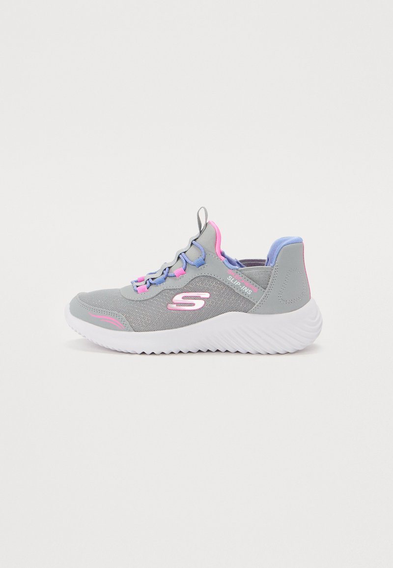 Zapatilla deportiva gris con diseño sin cordones, que presenta acentos morados y rosas, parte superior texturizada y una suela ondulada blanca. Estructura ligera y flexible.