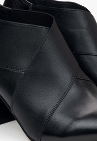 Czarne botki za kostkę z gładkiej skóry i szczegółami z teksturowanej tkaniny. Szpiczasty nos i blokowy obcas z bezszwowym wykończeniem.