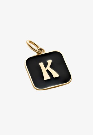 Amuleto de oro con forma cuadrada, con un fondo negro y una "K" blanca destacada. Textura suave con un acabado brillante.