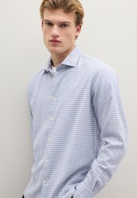 Camicia a quadri vichy bianca e azzurra in tessuto leggero, con chiusura frontale con bottoni, colletto a punta e maniche lunghe.