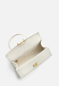 Sac à main en cuir blanc avec quincaillerie dorée, forme rectangulaire, anse supérieure et intérieur ouvert comportant une poche zippée et une texture lisse.