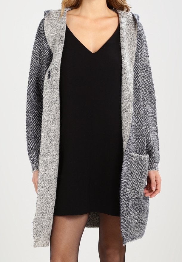 Femme portant une robe noire à col en V et un long cardigan gris texturé à capuche avec des poches avant.