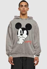 Szürke kapucnis pulóver, nagy fekete-fehér Mickey Mouse grafikával és piros aláírással. Puha tapintású, lazán illeszkedő fazonnal és kapucnival.