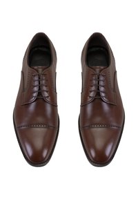 Een paar gepolijste bruin leren nette schoenen met veters en decoratieve perforaties op de neus, van bovenaf gezien op een witte achtergrond.