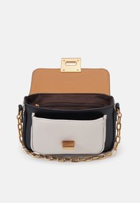 Small handbag with a dark blue body, light gray front pocket, gold chain strap, and a gold clasp closure. Interior has a brown lining.