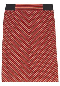 Jupe à mi-mollet avec un motif en chevron rouge, bleu marine et beige. La taille noire contraste avec le tissu texturé de la jupe.