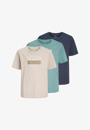 Maglietta verde menta con toppa con logo bianco, abbinata a jeans azzurri a gamba dritta e scarpe nere in suede. Design semplice, vestibilità rilassata.