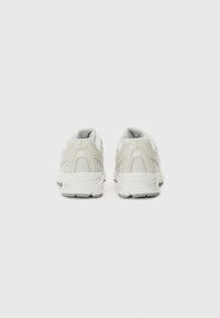 Vue arrière de chaussures de course gris clair avec un dessus texturé, un col rembourré et un détail de logo sur le talon. Elles sont dotées d'une semelle blanche rembourrée.