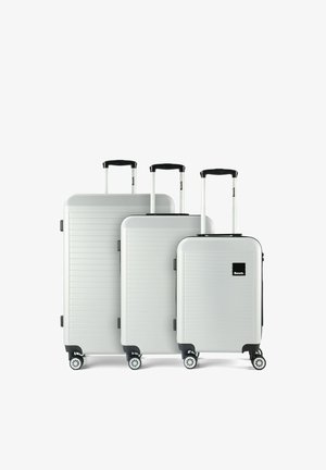 Drei weiße Hartschalenkoffer in verschiedenen Größen, mit ausgezogenen schwarzen Griffen und vier drehbaren Rädern, nebeneinander angeordnet.