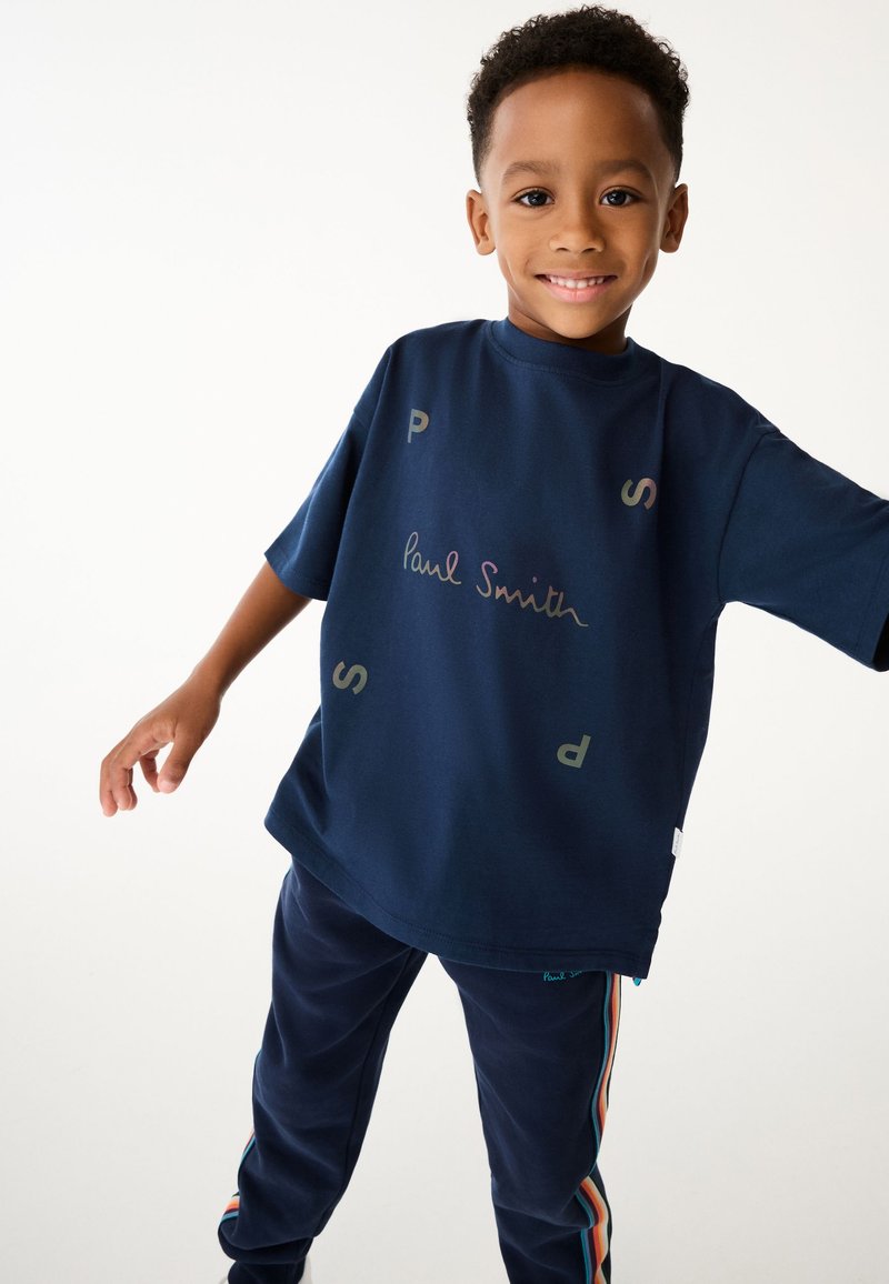 Marinblå oversized t-shirt med Paul Smith-logotyp, med grafiska detaljer och korta ärmar. Kombineras med matchande byxor som har färgade sidostringar.
