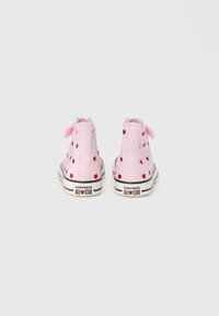 Ροζ υφασμάτινα ψηλά παπούτσια με κόκκινα σχέδια καρδιάς, μαύρες λαστιχένιες σόλες και λευκές λεπτομέρειες με το σήμα "Converse All Star" στη φτέρνα.