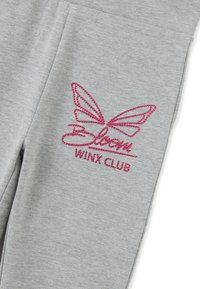 Tela gris claro con diseño de alas de mariposa en pedrería rosa y texto "Bloom Winx Club" en la manga de la prenda.