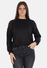 Felpa nera con maniche lunghe, scollo rotondo e dettagli decorativi sulle spalle. Tessuto morbido, vestibilità rilassata con un design cropped.