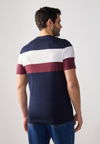 Short-sleeve shirt with navy, white, and burgundy horizontal stripes. Cotton blend fabric with a crew neckline, soft texture, and relaxed fit.