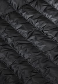 Schwarze Pufferjacke aus Stoff mit steppmuster. Verfügt über horizontale, gepolsterte Abschnitte, glatte Textur und glänzende Oberfläche.