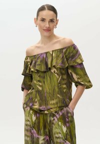 Top verde off-the-shoulder con cuello volado, que presenta un patrón botánico en tonos morados y beiges, hecho de tejido ligero.