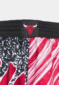 Mustat joustavat vyötärönauhat punaisella Chicago Bulls -logolla koripalloshortseissa, joissa on punaisia, valkoisia ja mustia abstrakteja kuvioita.