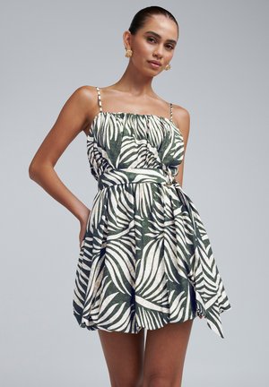 Floral-printed dress featuring green palm leaf designs on a cream background, with a fitted bodice, ruffled neckline, and adjustable straps.