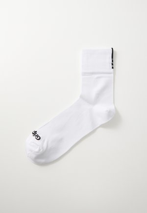 Valkoinen sukka, joka on valmistettu sileästä kankaasta ja jossa on ribbikuvioitu varsi. Tämässä on musta logo ja kolme mustaa raitaa lähellä ykköstä. Vakiokokoinen urheilumuoto.