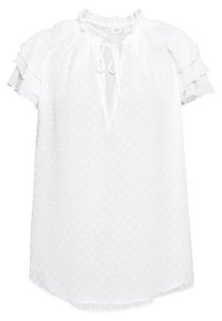 Vit kortärmad blus med strukturerade prickar, volangärmar och en knytning i kragen med nyckelhål.