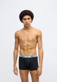 Μαύρα μπόξερ briefs με ελαφρώς γαλάζια ζώνη μέσης με το λογότυπο της Nike. Βαμβακερό υλικό με άνετη εφαρμογή, διαθέτουν μπροστινή θήκη και κοντά πόδια.