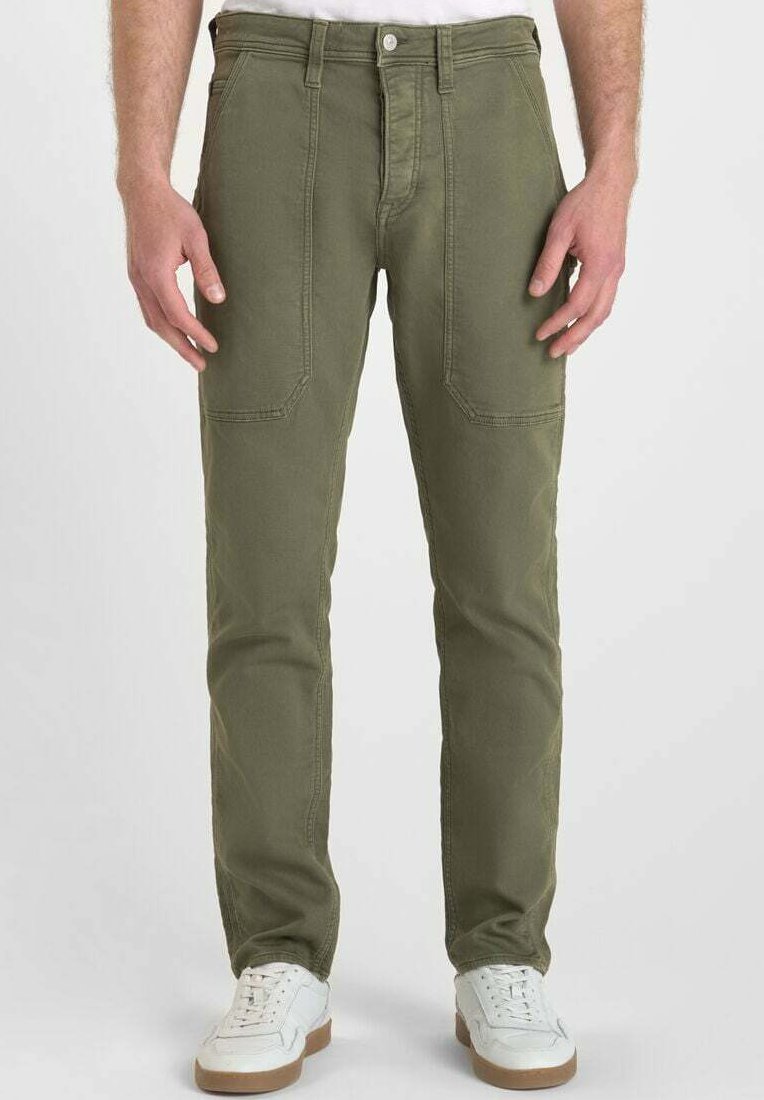 Pantalons en coton vert olive avec une coupe droite, dotés de poches avant et de coutures renforcées, associés à des baskets blanches.