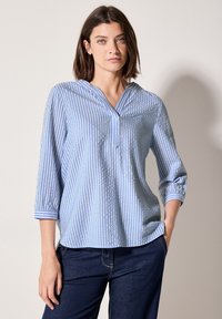 Chemisier rayé bleu et blanc avec un col à patte, des manches trois-quarts et une coupe décontractée. Fabriqué en tissu léger avec une texture lisse.