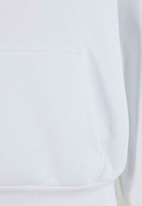 Hoodie blanc en tissu doux, avec une poche frontale et des poignets côtelés. Texture lisse sans motifs ni graphismes visibles.