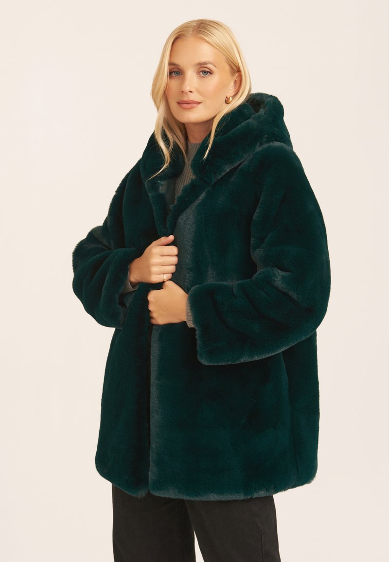 Dark green faux fur coat with a hood, oversized fit, wide sleeves, and a plush texture. Features a straight hem and no visible closures.