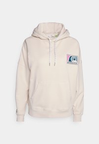 Sudadera color crema hecha de un tejido suave, con un bolsillo frontal, capucha ajustable con cordones y un parche con el logo de Quiksilver en el pecho.