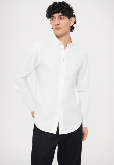 Camicia bianca a maniche lunghe con bottoni, realizzata in tessuto liscio, con colletto abbottonato e un piccolo logo sul petto.