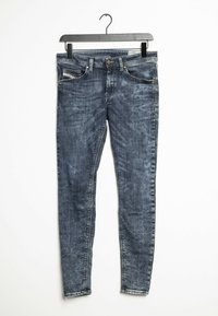 Vaqueros ajustados de denim azul oscuro, con un lavado desgastado, cinco bolsillos y cierre de botón con cremallera metálica.