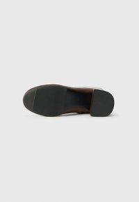 Brown leather shoe sole with a smooth finish, featuring a textured black rubber grip and a slight heel. Overall flat design.