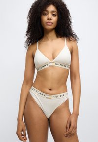 Βαμβακερό σουτιέν και στρινγκ με διακριτικό λογότυπο σε ανοιχτό μπεζ χρώμα. Το σουτιέν έχει τριγωνικό σχήμα με λεπτές τιράντες και διακοσμητικά λογότυπα. Το στρινγκ διαθέτει ταιριαστή ζώνη μέσης.